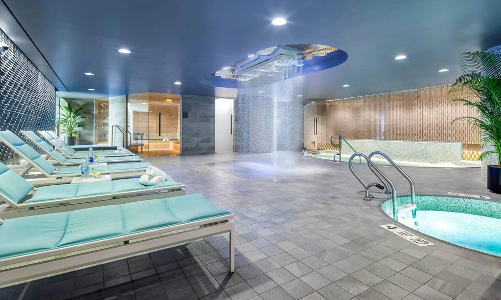 a spa with a jacuzzi and a pool in a room with chairs at SKY Apartments, New York, 10036