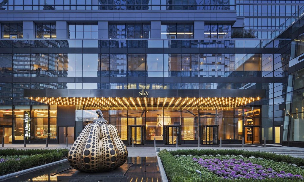 a large building with a sculpture in front of it at SKY Apartments, New York, NY, 10036