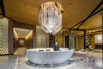 a man stands in the lobby of a hotel with a large circular desk and a at SKY Apartments, New York, New York