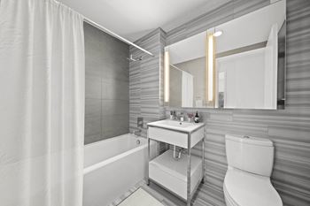 a bathroom with a tub and a sink and a mirror at SKY Apartments, New York