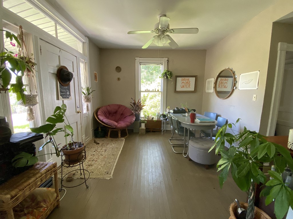 a living room with a table and chairs and a ceiling fan