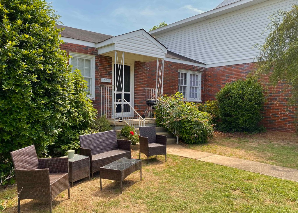 a patio with chairs in front of a brick house