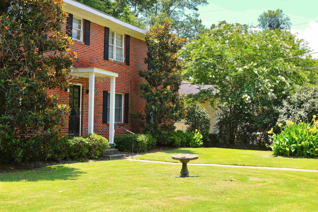 a yard with a bird bath in front of a brick house