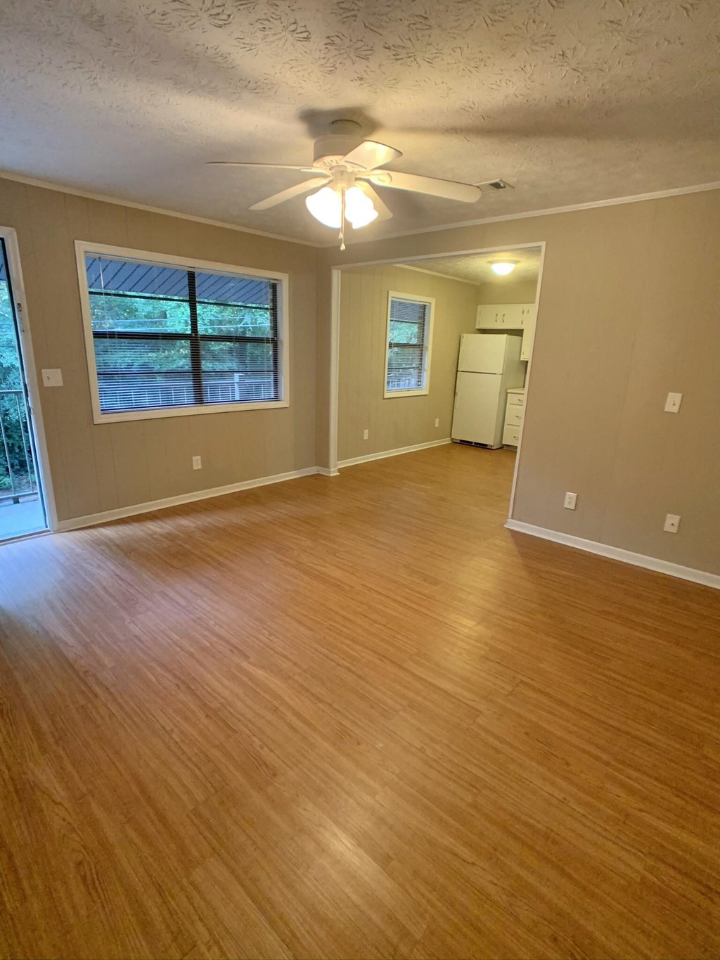 an empty living room with wood floors and a ceiling fan