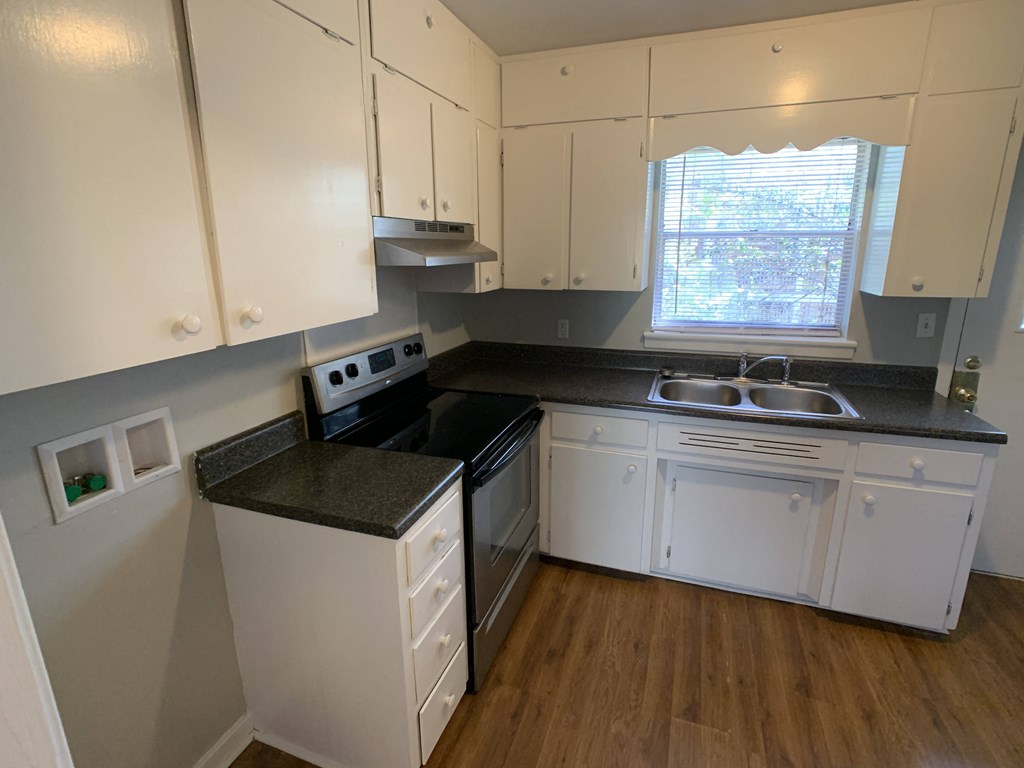 an empty kitchen with white cabinets and black counter tops