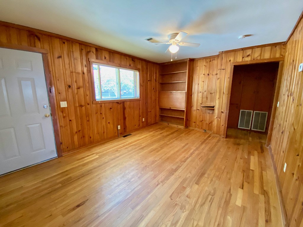 an empty living room with wooden walls and wood floors