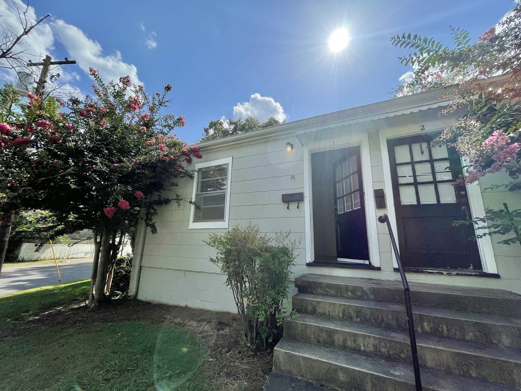 the front of a white house with stairs and a blue door