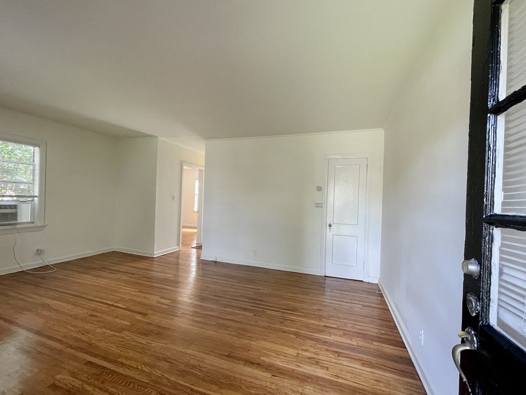 an empty living room with wood floors and white walls