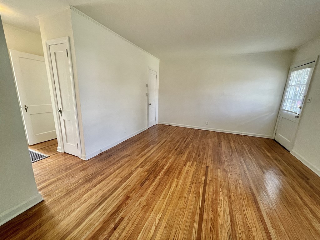 an empty living room with wood floors and white walls