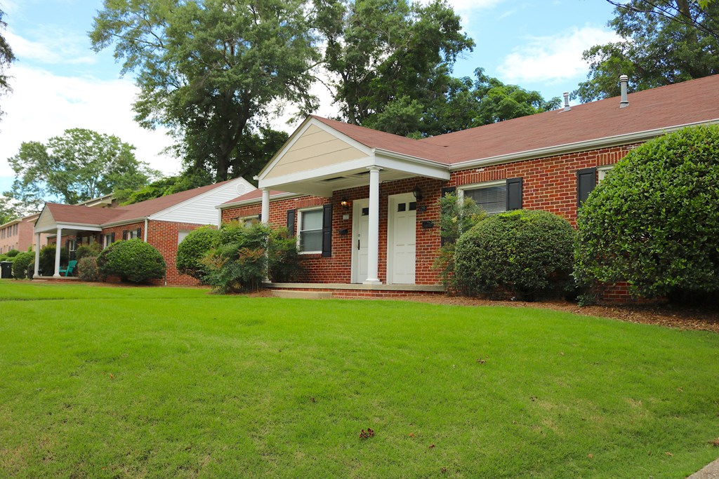the front of a brick house with a green lawn
