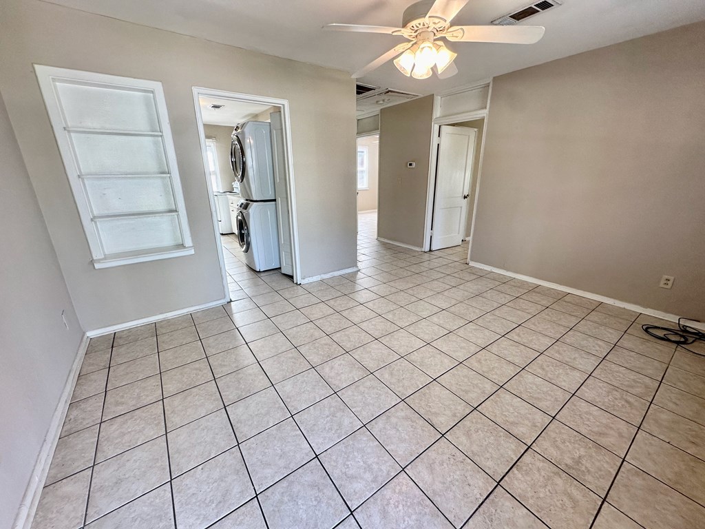 an empty living room with tile flooring and a ceiling fan