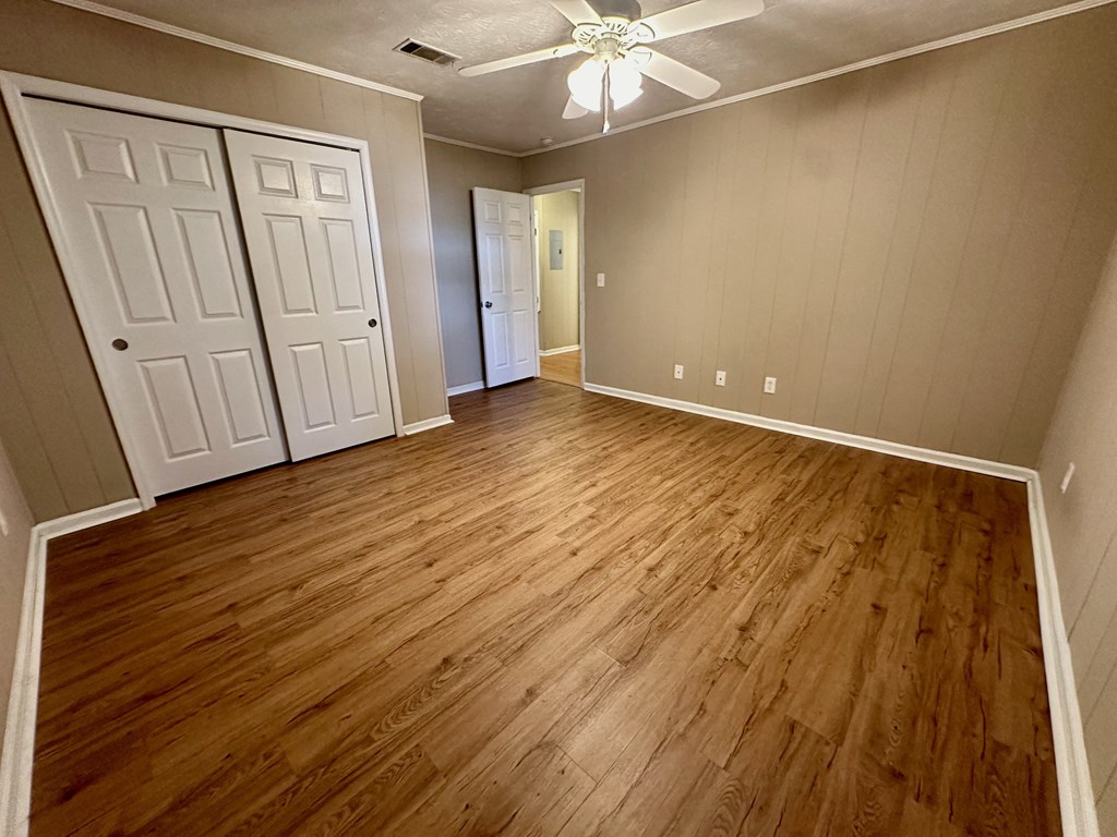an empty living room with wood floors and a ceiling fan