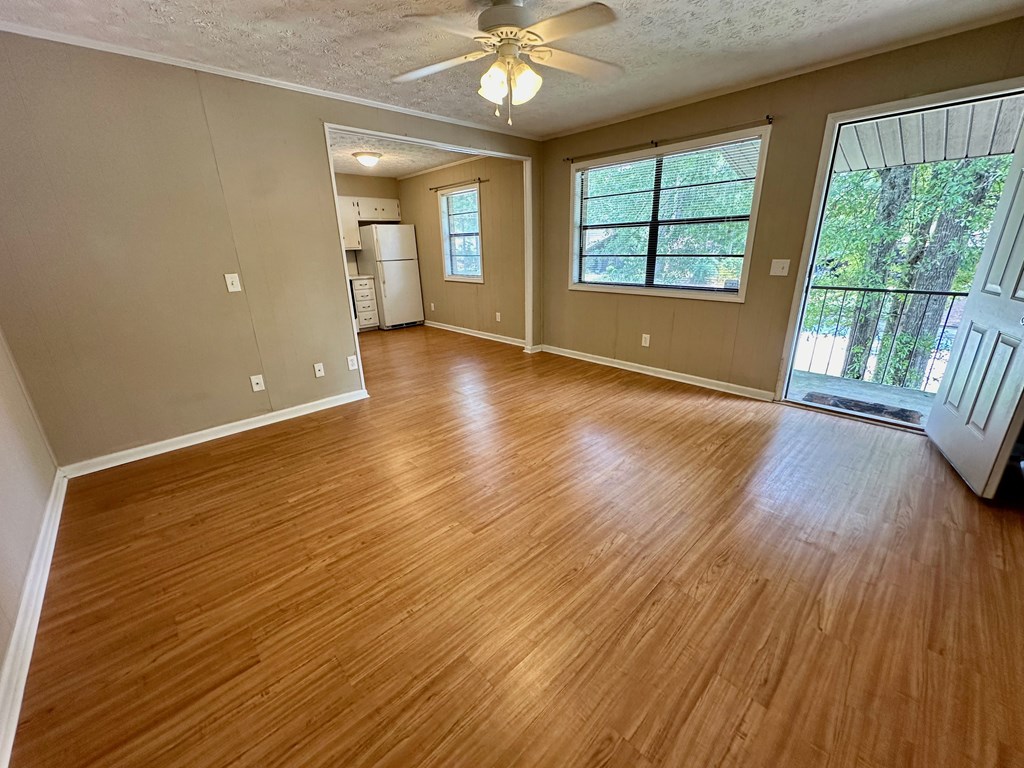 an empty living room with wood floors and a ceiling fan