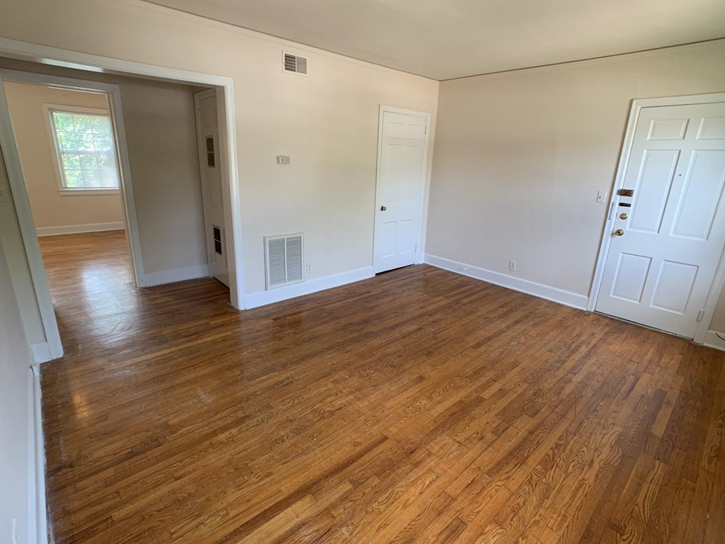 an empty living room with wooden floors and white walls