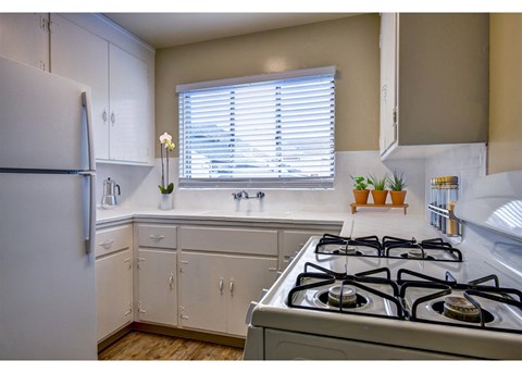 A kitchen with a white gas stove and white cabinets.