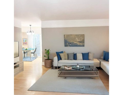 A living room with a white couch, a coffee table, and a painting on the wall.