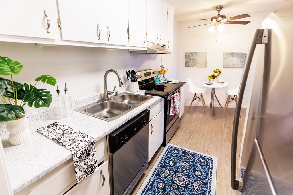 A kitchen with a sink, stove, and refrigerator.