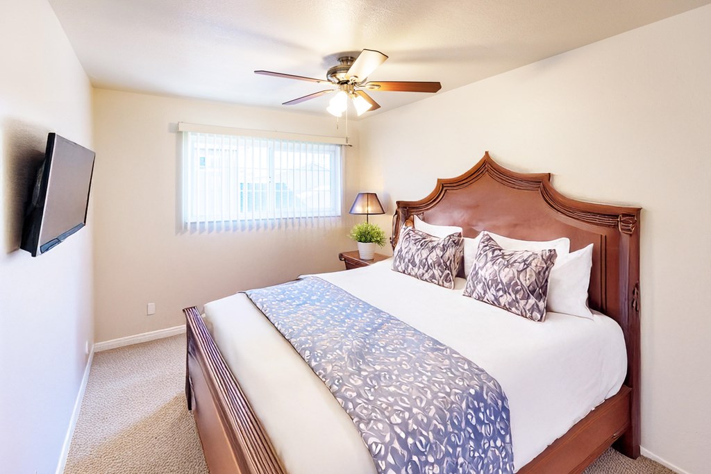 A bedroom with a bed, a ceiling fan, and a window.