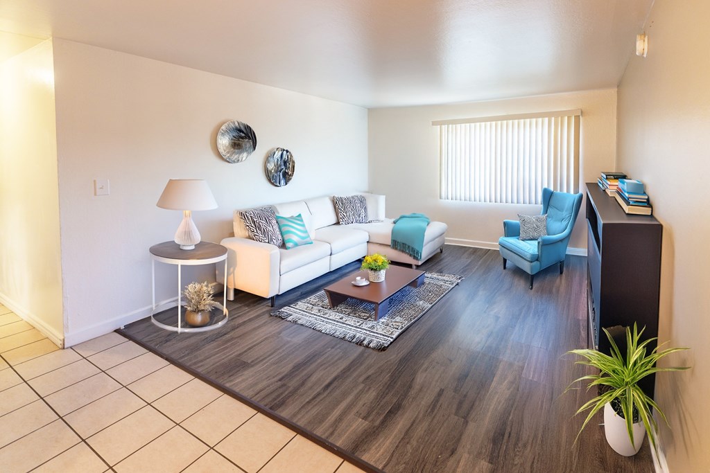A living room with a white couch, blue chairs, and a wooden floor.