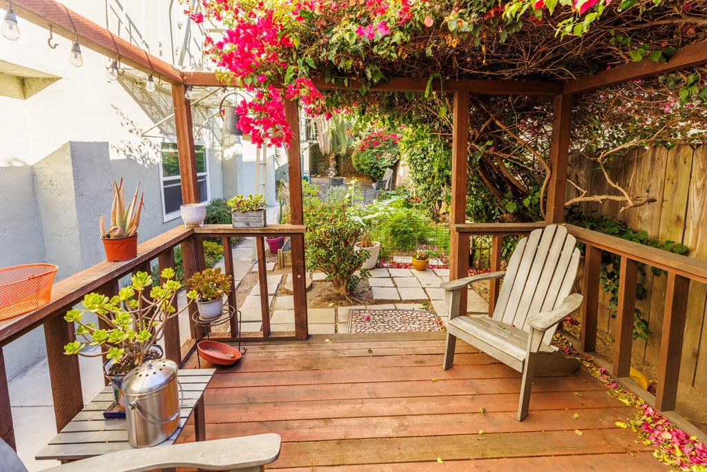 A wooden deck with a bench and a table with flowers on it.