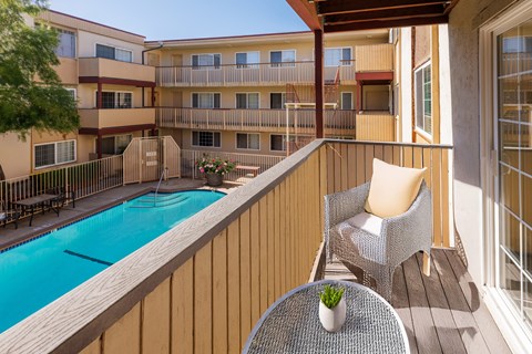 A balcony with a table and chairs overlooking a pool.