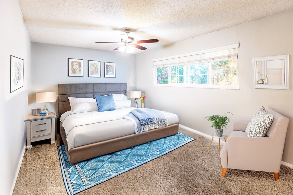 A bedroom with a bed, a chair, and a ceiling fan.