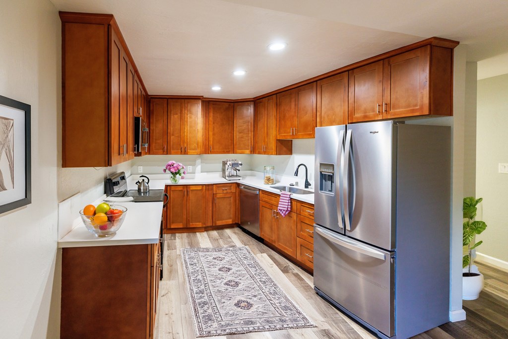 A kitchen with wooden cabinets and a stainless steel refrigerator.
