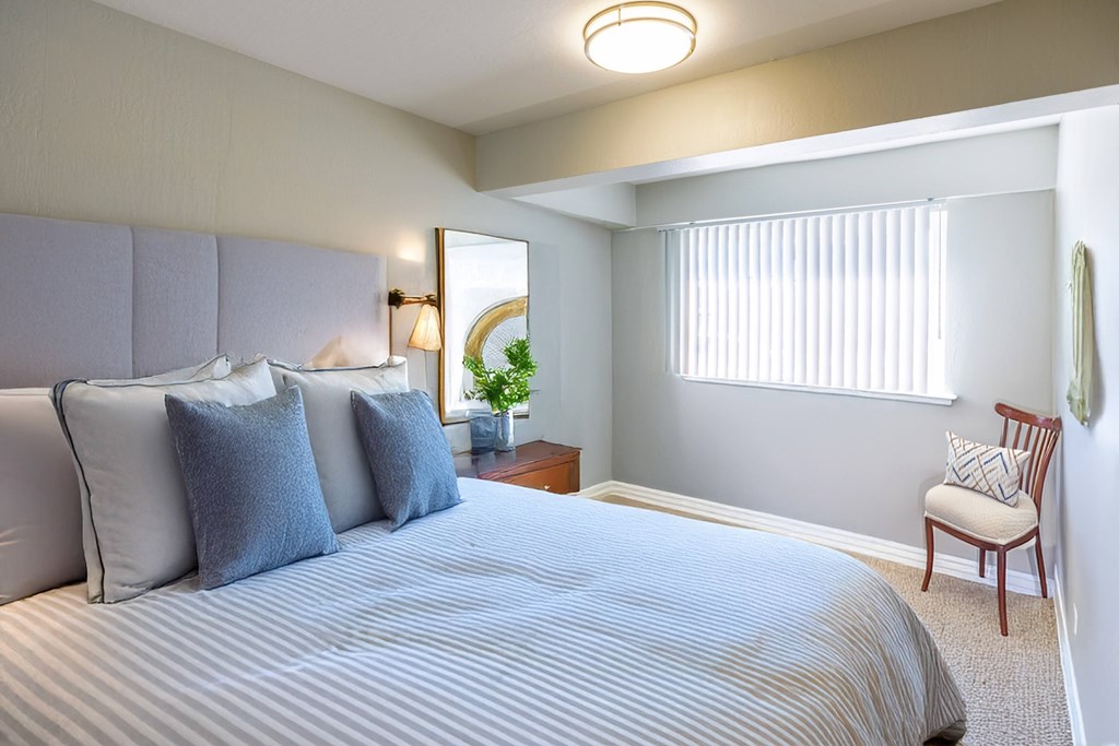 A bedroom with a large bed and a chair.