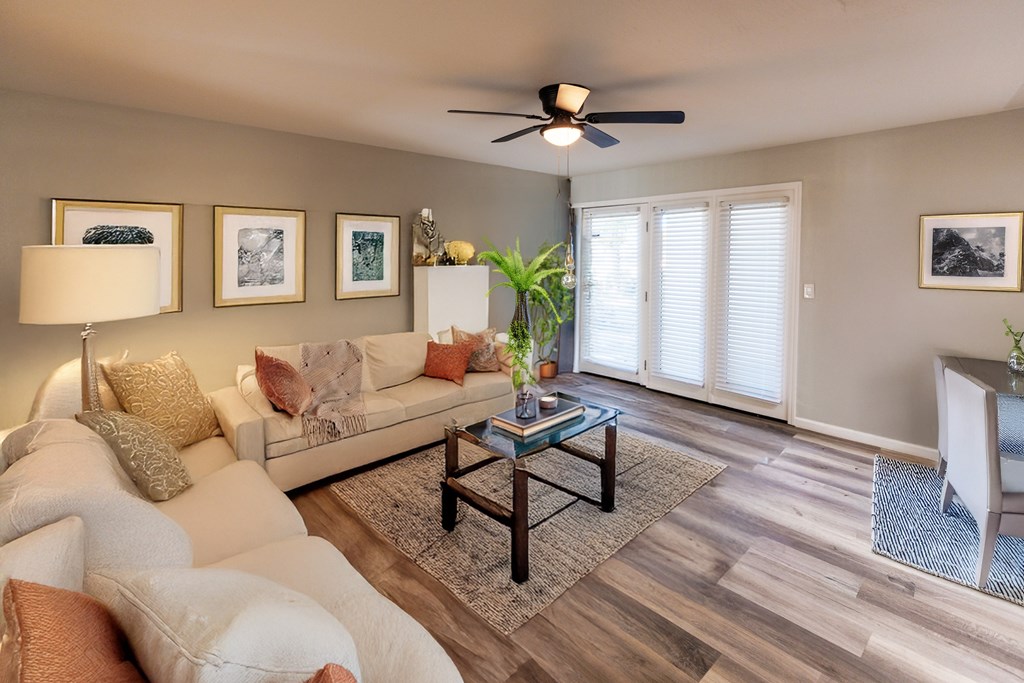 A living room with a white couch, a coffee table, and a ceiling fan.