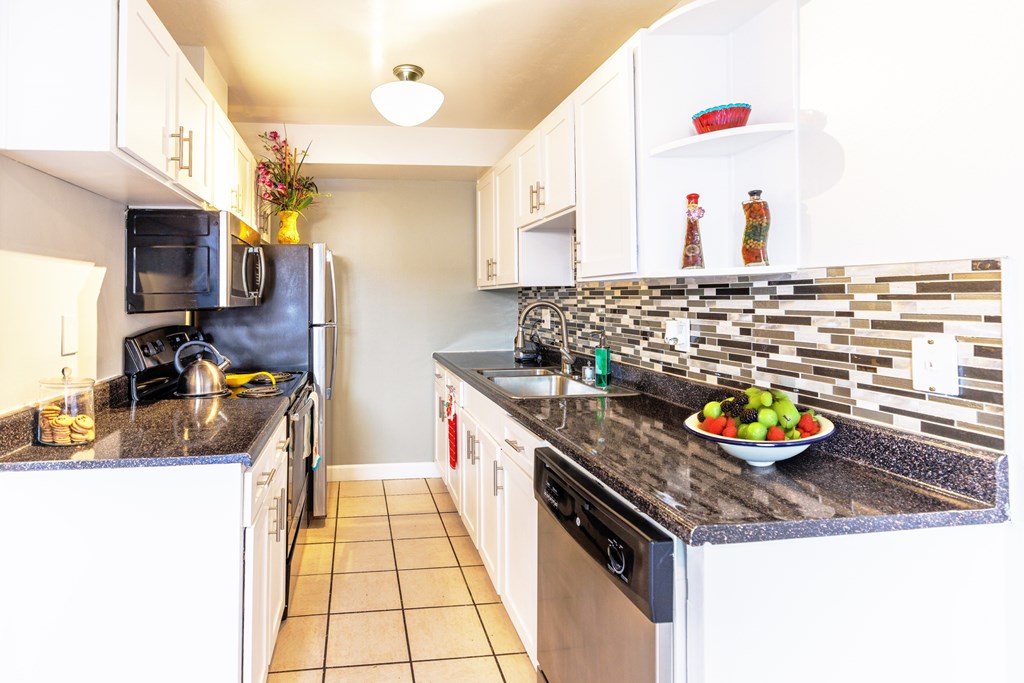 A kitchen with black granite countertops and white cabinets.