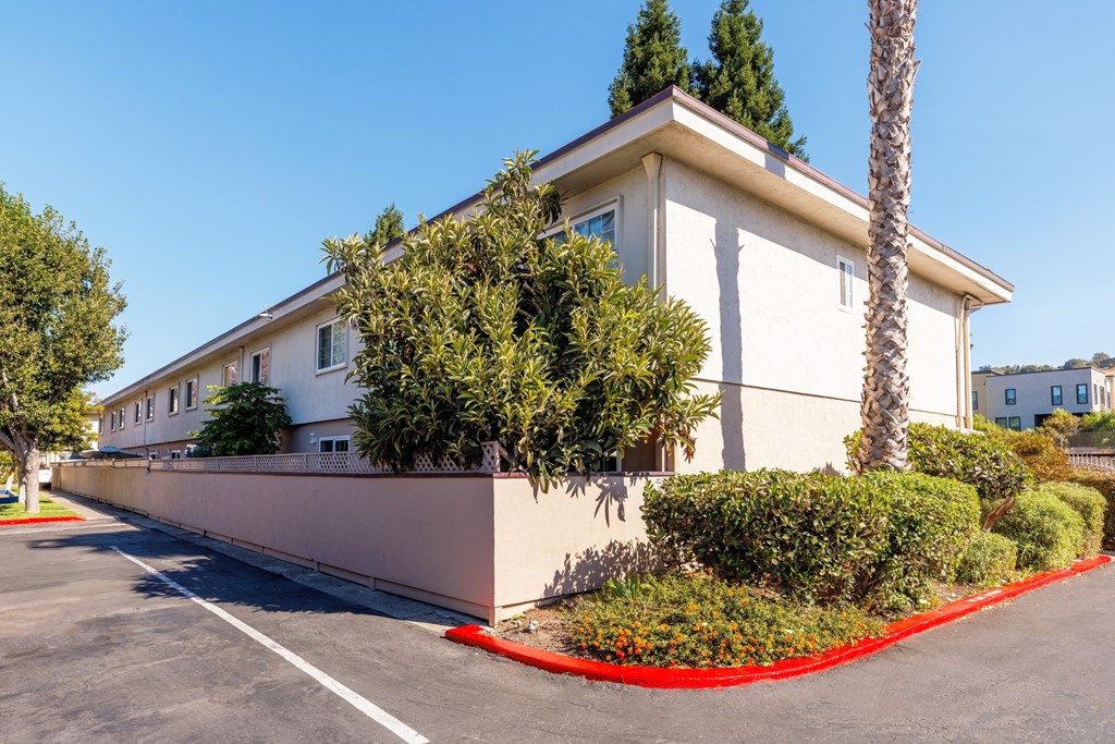 A white building with a red border around the bushes.