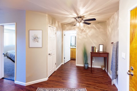 A hallway with a ceiling fan and a rug on the floor.