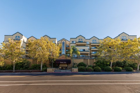 A row of apartment buildings with trees in front.