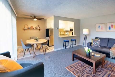 A living room with a grey couch, a coffee table, and a dining table with chairs.