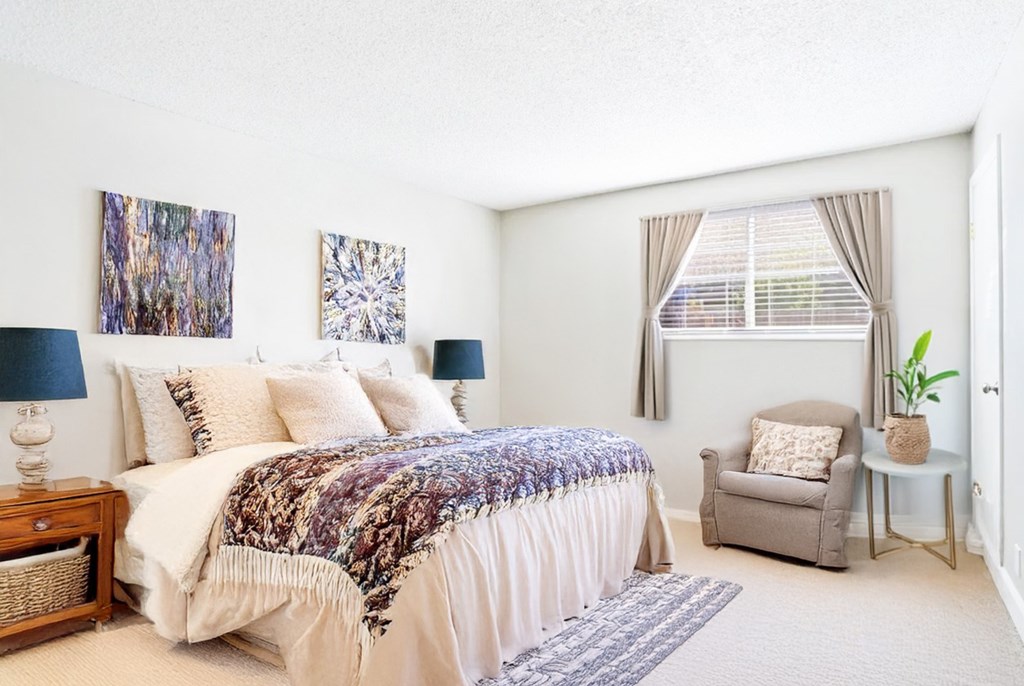 A bedroom with a large bed and a chair.