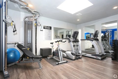 a gym with treadmills and other exercise equipment in a room with a mirror