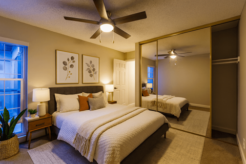 A bedroom with a large bed and a mirrored closet door.