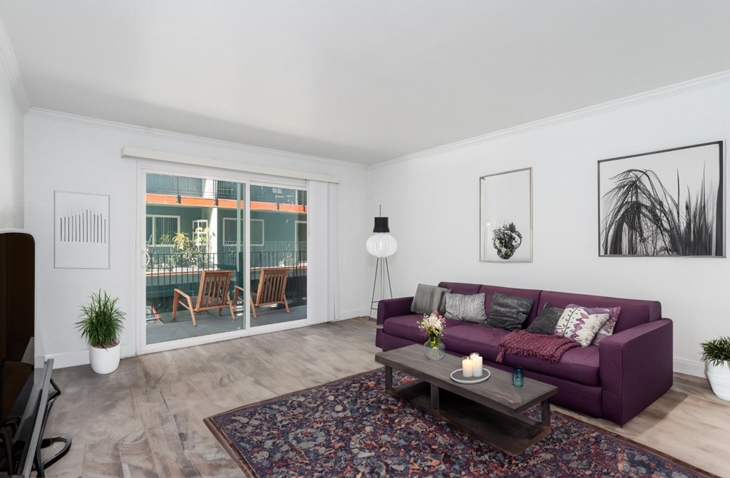 A living room with a purple couch and a rug.