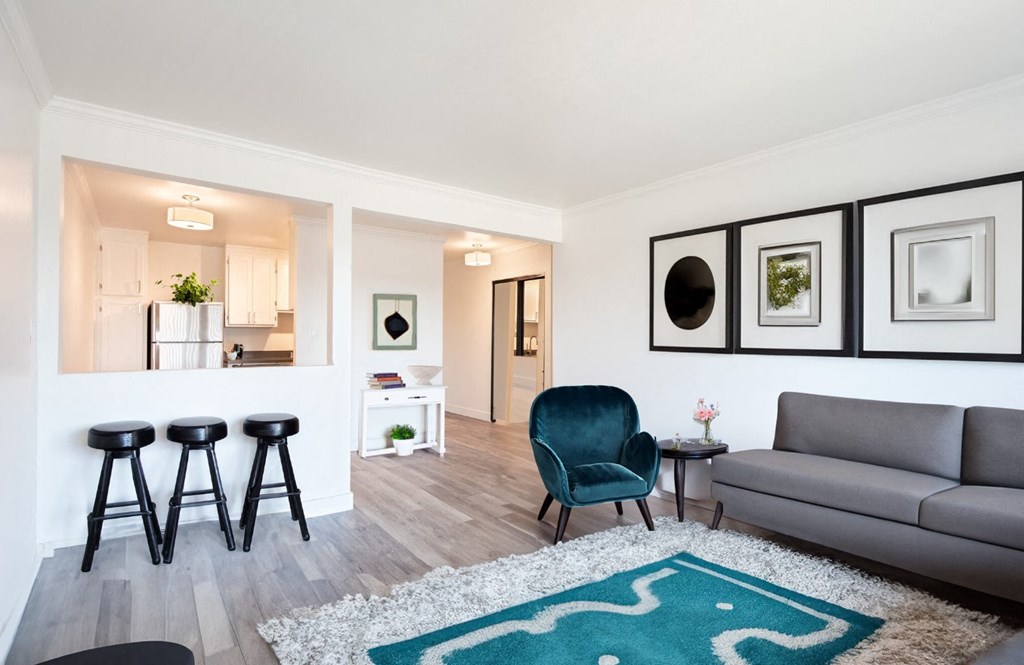 A living room with a grey couch, a blue chair, and a white rug.
