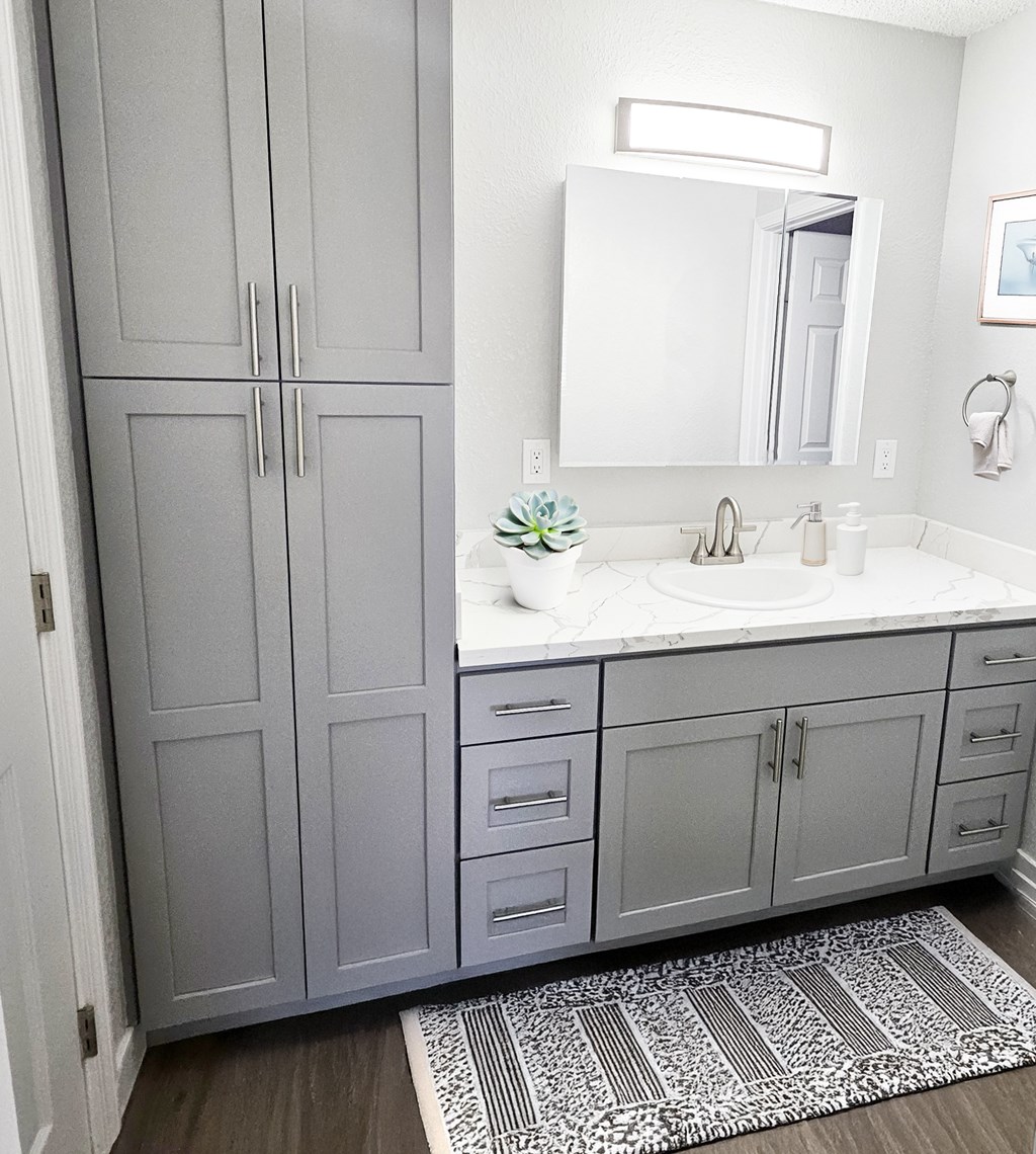 A bathroom with a sink, mirror, and cabinets.