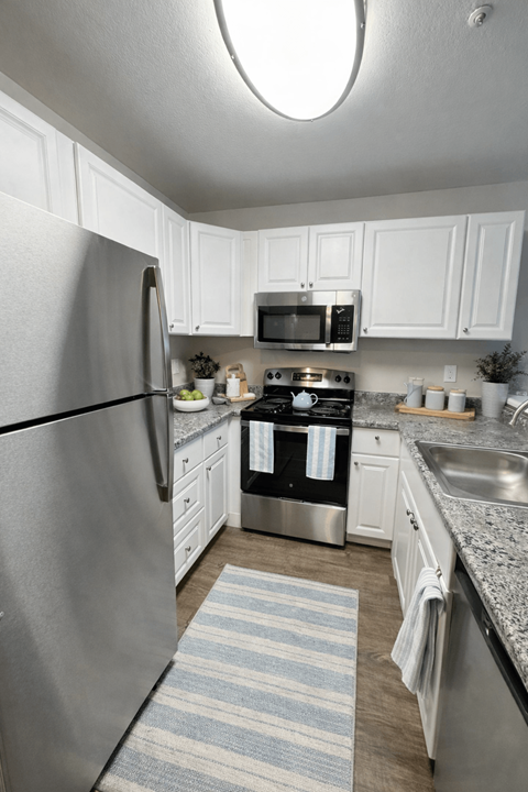 A kitchen with a refrigerator, microwave, oven, and sink.