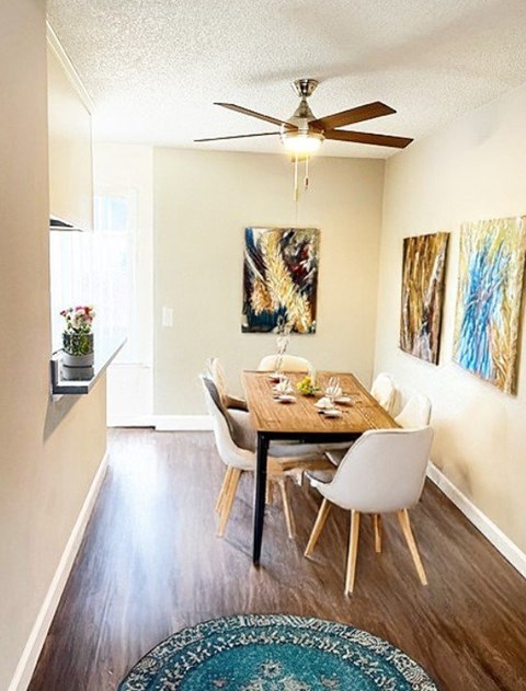 A dining room with a table set for two and a ceiling fan.