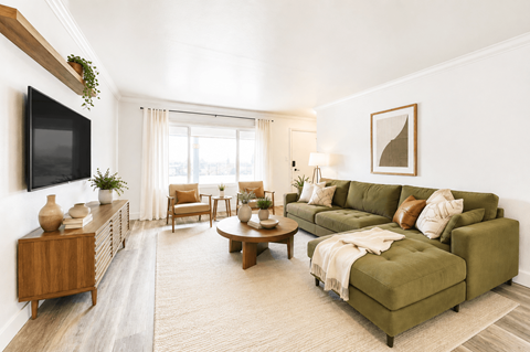 A living room with a green couch and a wooden cabinet.