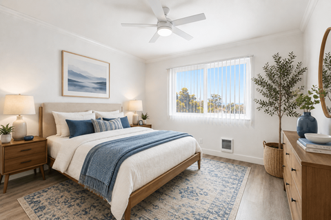 A bedroom with a bed, nightstand, and a plant.