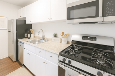 A modern kitchen with a black fridge, white cabinets, and a white stove top oven.