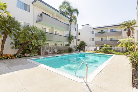 A swimming pool in front of a white apartment building.