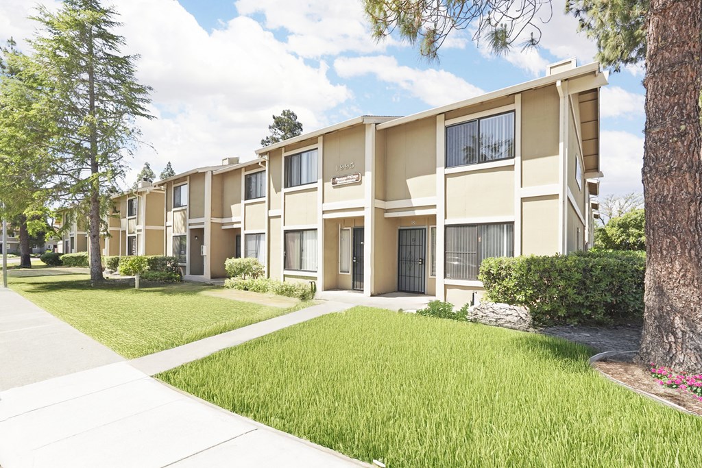 Apartment complex with green grass and trees.
