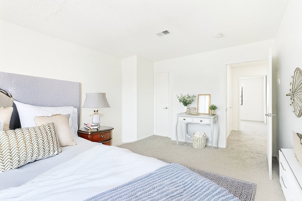 A bedroom with a large bed and a desk with a lamp.