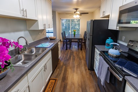 A kitchen with a black fridge and wooden floors.