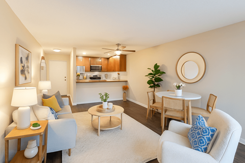 A living room with a white couch, a coffee table, and a dining table with chairs.